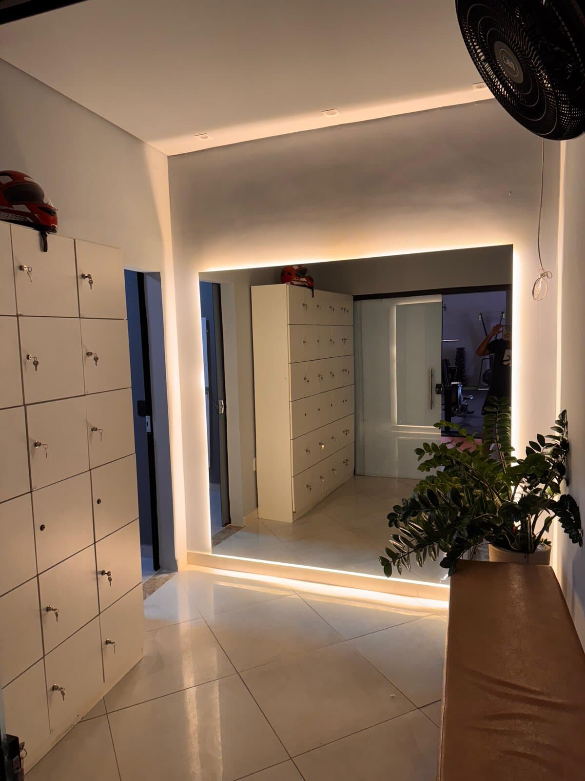 Recepção da FS Studio, com parede de armários brancos com chave e iluminação embutida.